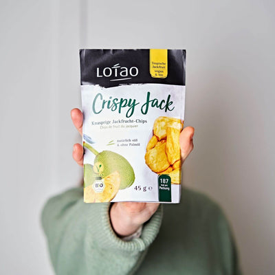 Hand hält eine 45g Tüte von Lotao Crispy Jack, den natürlich süßen knusprigen Jackfruit Chips in Bio-Qualität ohne Palmöl