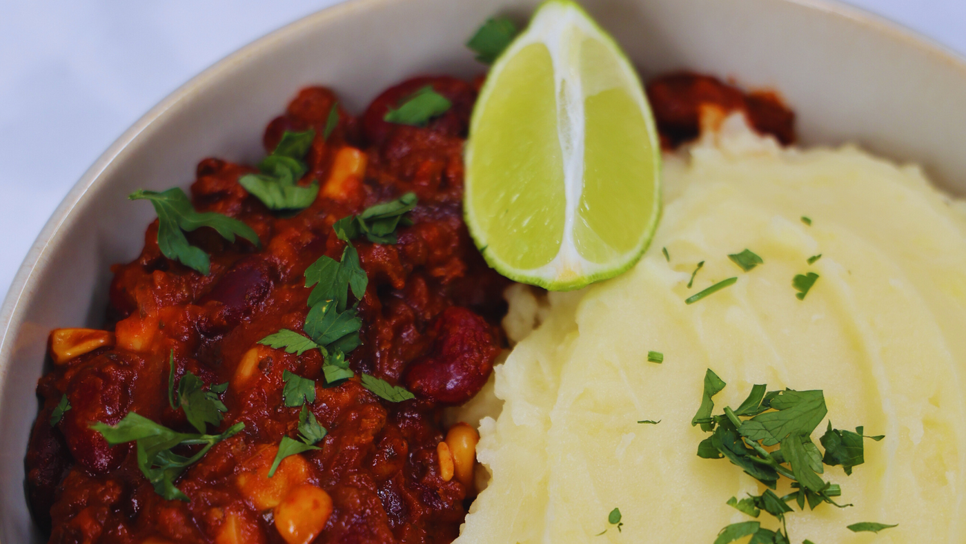 Chili sin Carne mit Kartoffelstampf und einer Limette serviert
