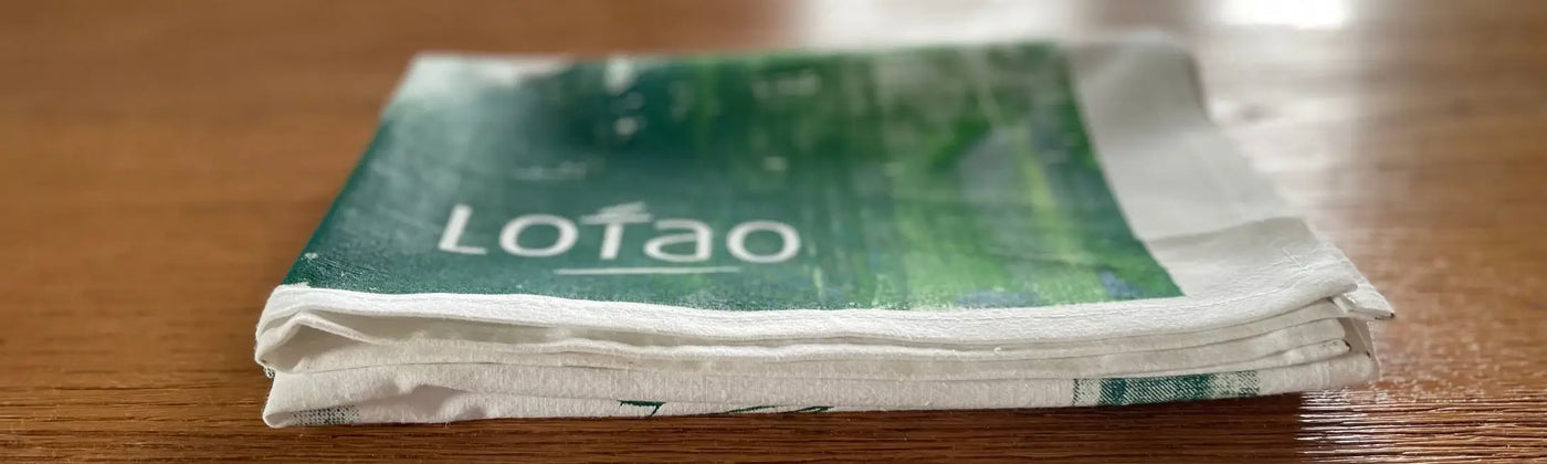 In der Kategorie Bundles & Geschenke bietet Lotao hochwertige Geschenksets und Küchenutensilien für vegane Ernährung und vegane Lebensmittel, hier im Kategoriebanner Desktop mit gefaltetem Lotao-Küchenhandtuch auf Holztisch – ideal für vegan für Anfänger und als vegane Kochbox.