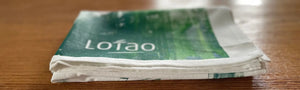 In der Kategorie Bundles & Geschenke bietet Lotao hochwertige Geschenksets und Küchenutensilien für vegane Ernährung und vegane Lebensmittel, hier im Kategoriebanner Desktop mit gefaltetem Lotao-Küchenhandtuch auf Holztisch – ideal für vegan für Anfänger und als vegane Kochbox.