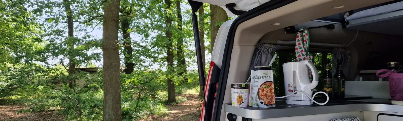 In der Kategorie Outdoor & Unterwegs präsentiert Lotao vegane und bio Fertiggerichte für unterwegs, hier im Kategoriebanner Desktop mit einer Camping-Küche im geöffneten Kofferraum vor Waldkulisse – ideale schnelle Fertiggerichte, Instant Gerichte und Fertiggerichte für den Wasserkocher.