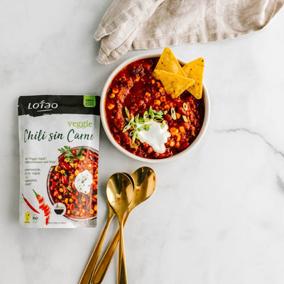 Angerichteter Teller und Packung mit Lotao Veggie Chili sin Carne Bowl, der veganen Bio-Mahlzeit mit schneller Zubereitung