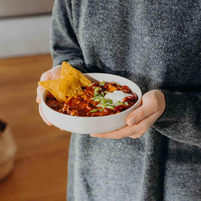Frau hält angerichteten Teller mit Lotao Veggie Mediterraner Bowl, der veganen Bio-Mahlzeit mit schneller Zubereitung