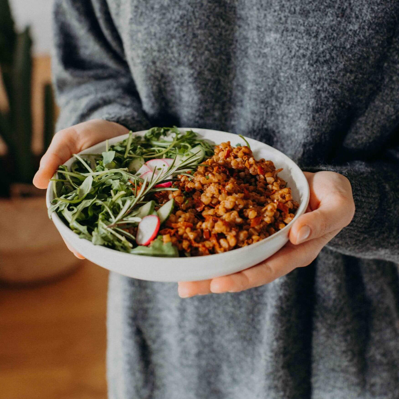 Frau hält angerichteten Teller mit Lotao Veggie Mediterraner Bowl, der veganen Bio-Mahlzeit mit schneller Zubereitung