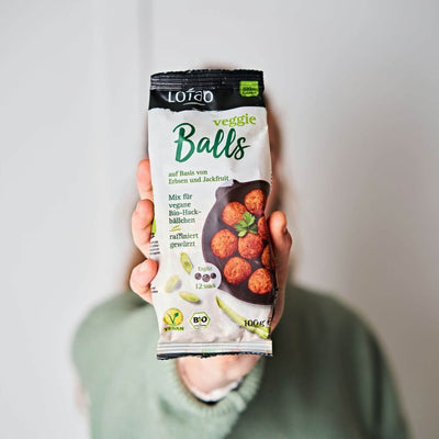 Hand hält eine 100g Packung vom Lotao Veggie Balls Mix, dem veganen Fleischersatz für saftige vegetarische Hackbällchen auf Basis von Jackfruit und Erbsen in Bio-Qualität. 