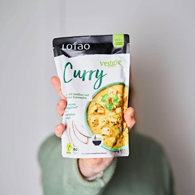 Hand hält 320g Packung Fertigsauce Veggie Curry von Lotao mit bio-veganer Fertigsosse mit Jackfruit als veganer Fleischersatz und Kokosmilch.