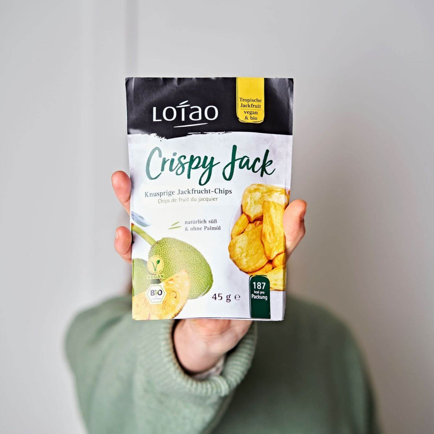 Hand hält eine 45g Tüte von Lotao Crispy Jack, den natürlich süßen knusprigen Jackfruit Chips in Bio-Qualität ohne Palmöl