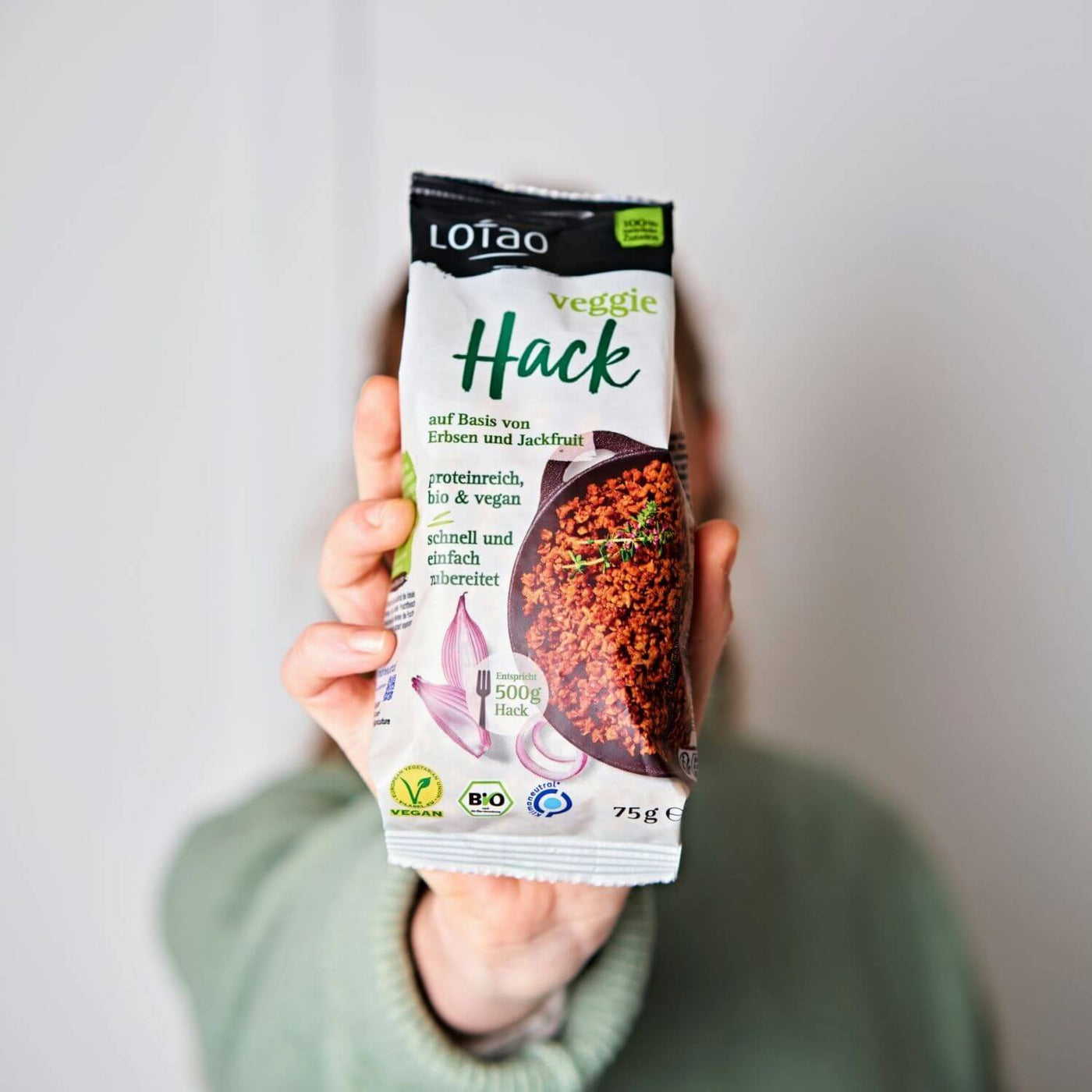 Hand hält eine 75g Packung vom Lotao Veggie Hack, dem veganen Fleischersatz auf Basis von Jackfruit und Erbsen in Bio-Qualität und mit einem Proteingehalt von über 70%. 
