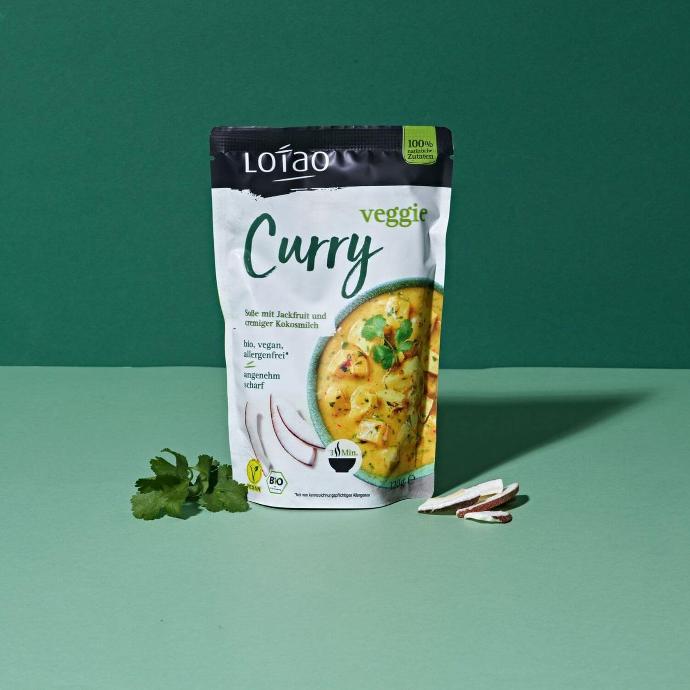 320g Packung Fertigsauce Veggie Curry von Lotao mit bio-veganer Fertigsosse mit Jackfruit als veganer Fleischersatz und Kokosmilch vor grünem Hintergrund
