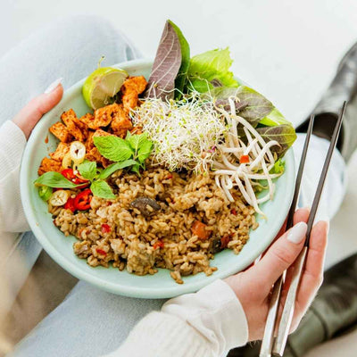 Frau hält angerichteten Teller mit Lotao Veggie Thai Bowl, der veganen Bio-Mahlzeit mit schneller Zubereitung